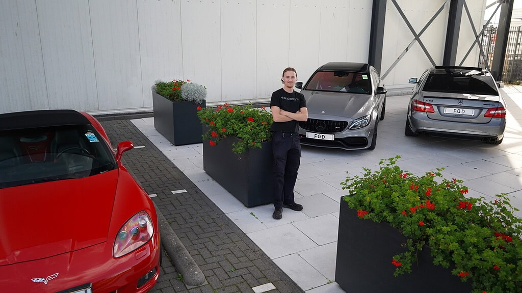 Quincy Dubelaar voor de loods van FQD in Velsen-Noord, met de occasions op het terrein.