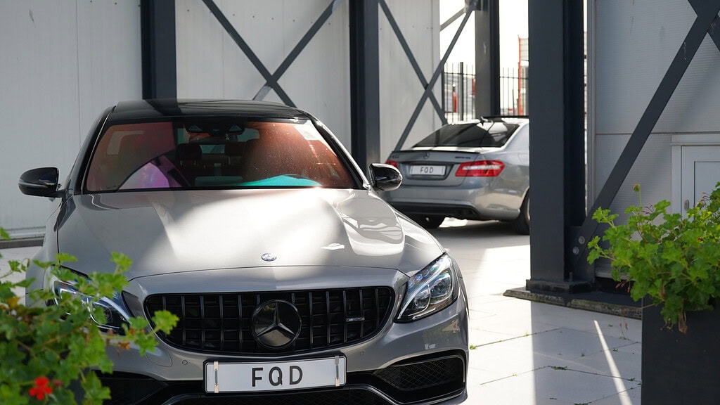 Grijze Mercedes-AMG met FQD-kenteken in de loods van FQD in Velsen-Noord, met geraniums op de voorgrond.